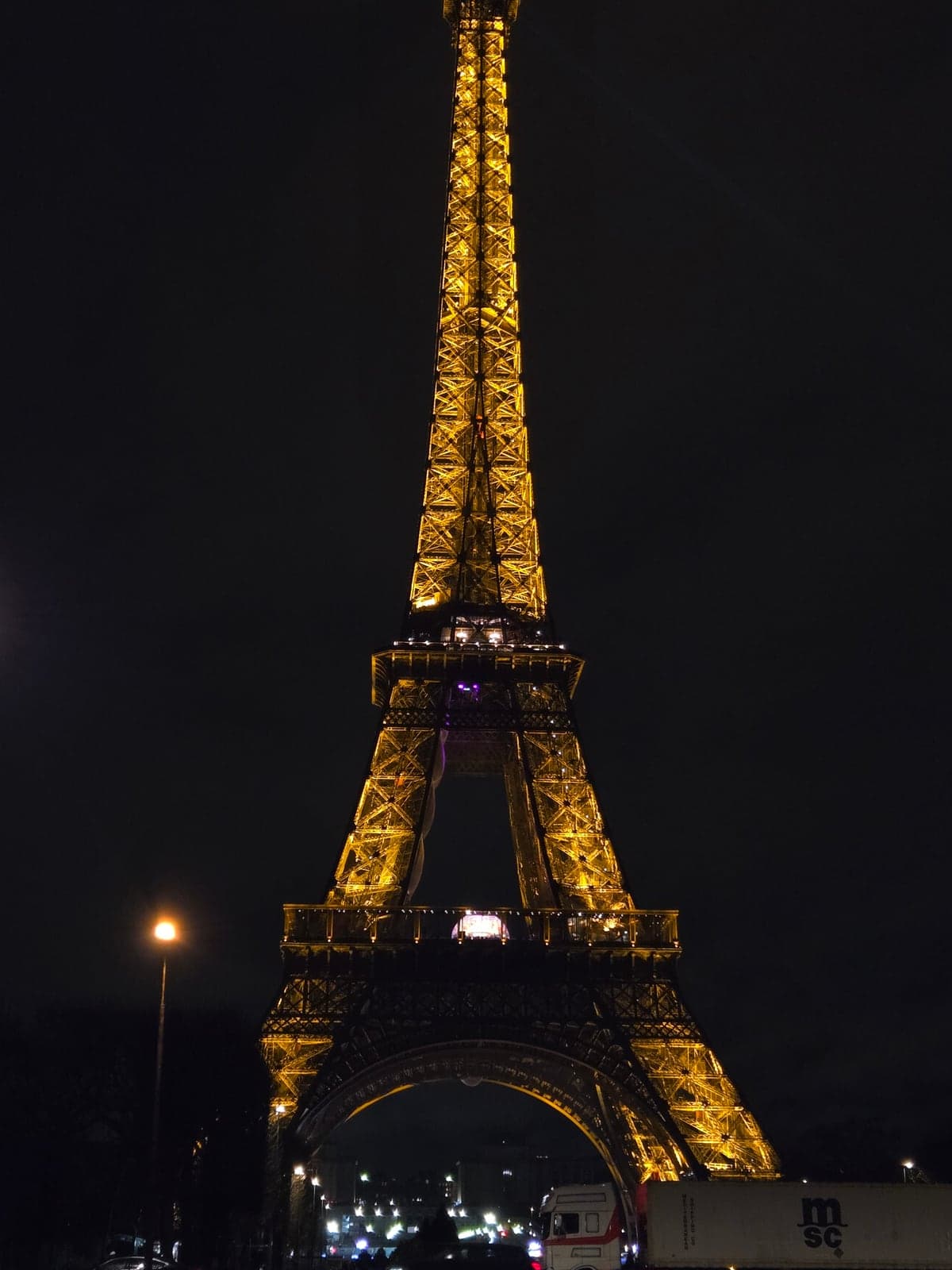 The Eiffel Tower glowing gold against the night sky.