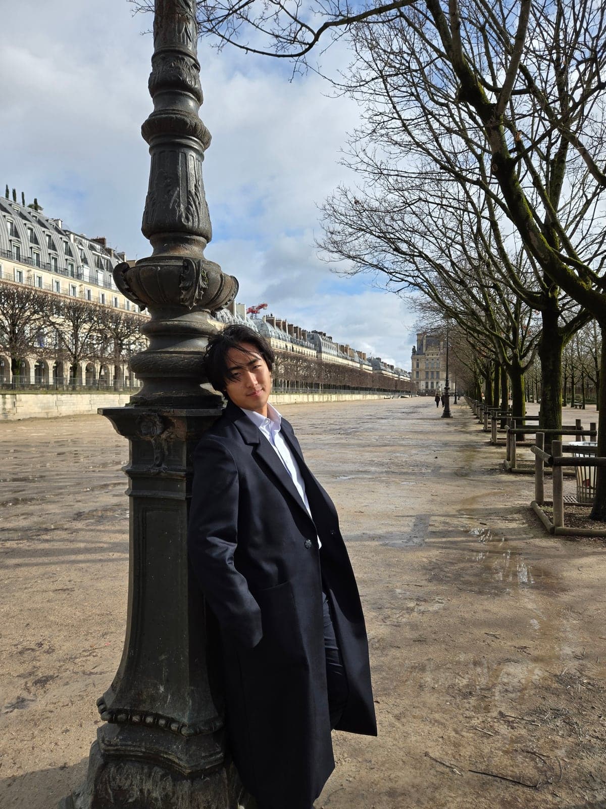 A portrait beside an ornate lamppost on a tree-lined Paris avenue.