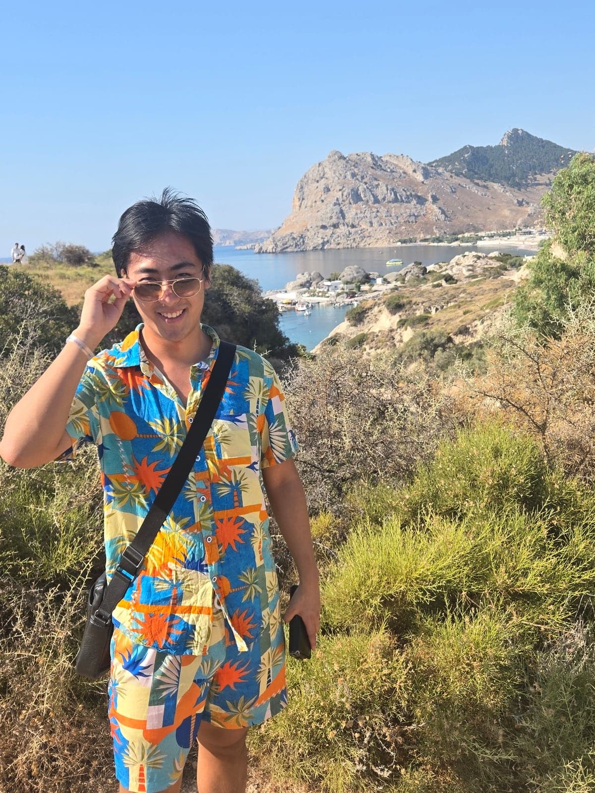 Max in a colourful shirt above a rocky coastline.
