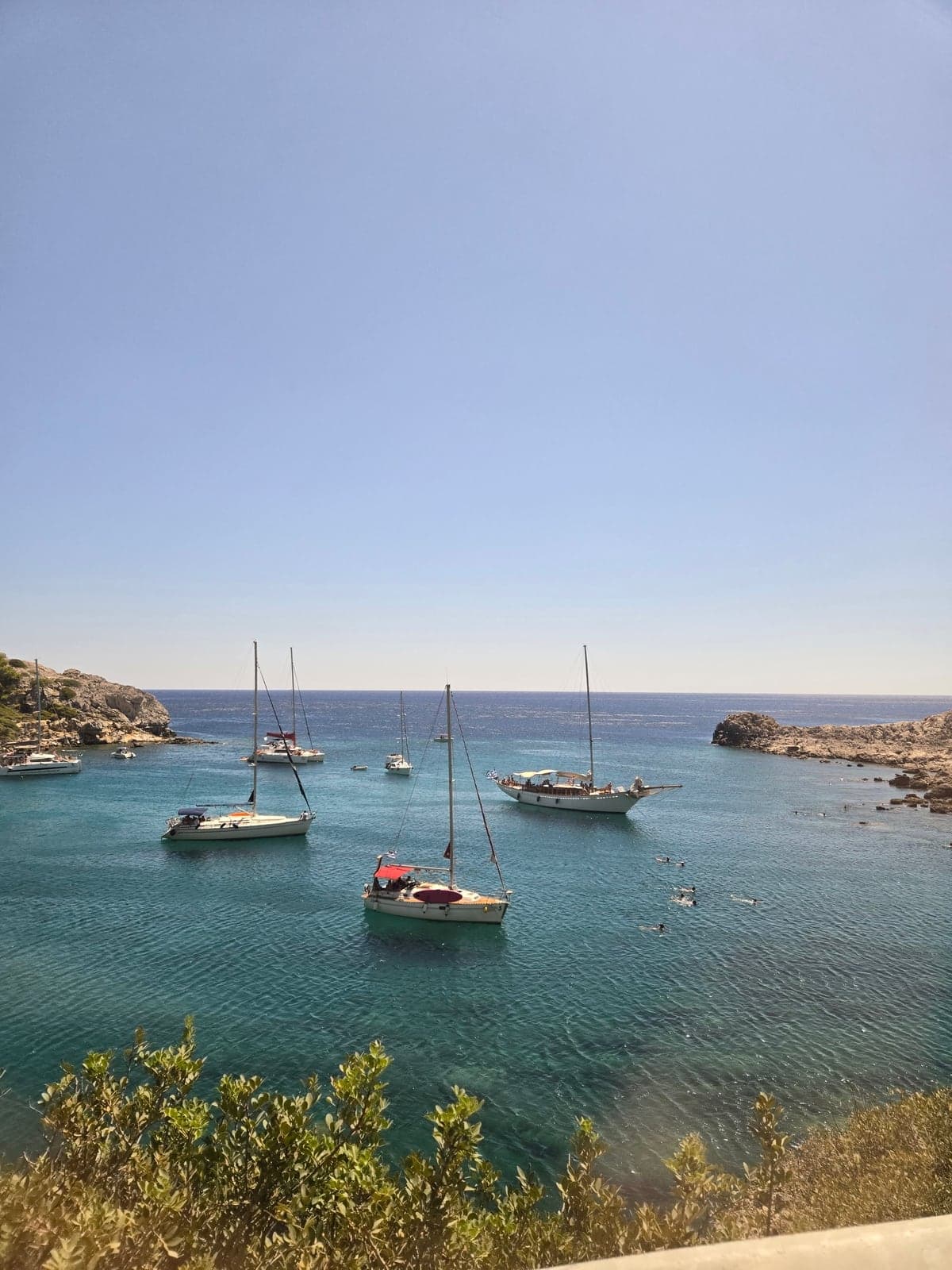 Small boats anchored in a sheltered turquoise bay.