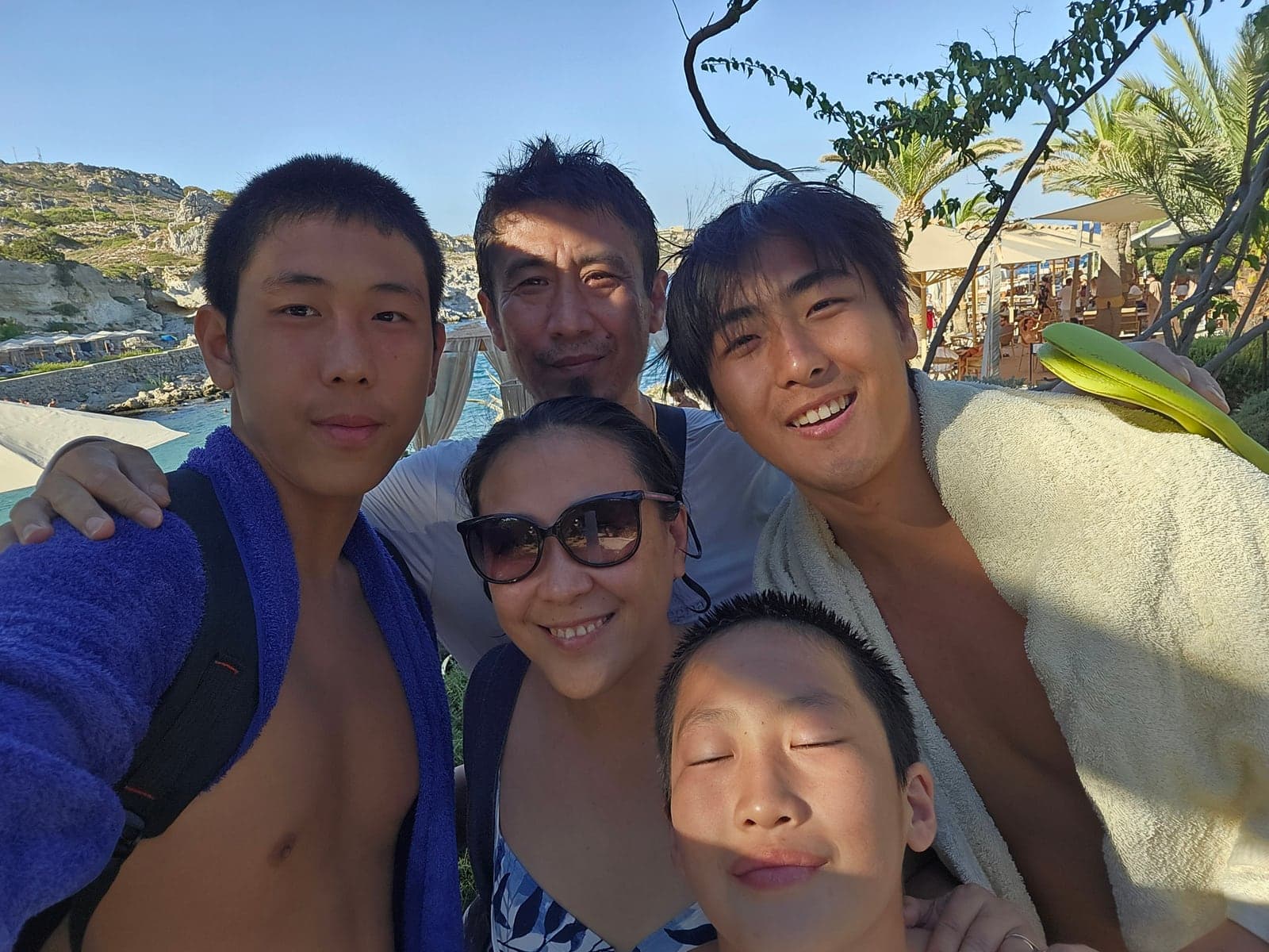 Five people smiling together for a group photograph outdoors.