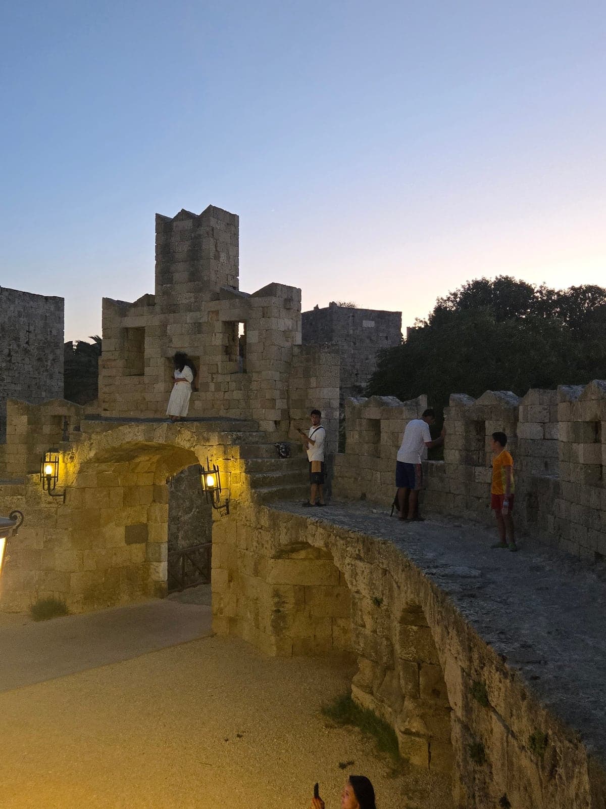 An illuminated stone gateway and towers at dusk.