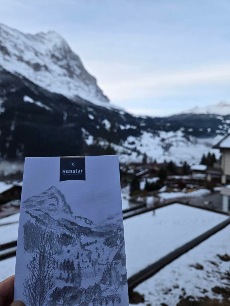 A mountain drawing held against the winter view in Grindelwald.